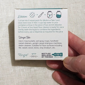 Hand holding a Tangie product packaging with instructions on a textured beige background