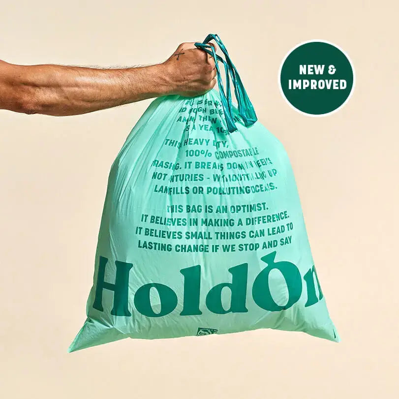 Teal compostable bag with text and 'HoldOn' branding, held by a person against a beige background.
