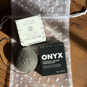 Cleansing facial bar, a konjac sponge and goat's milk moisturizer on a polka dot pouch