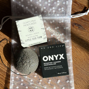 Cleansing facial bar, a konjac sponge and goat's milk moisturizer on a polka dot pouch