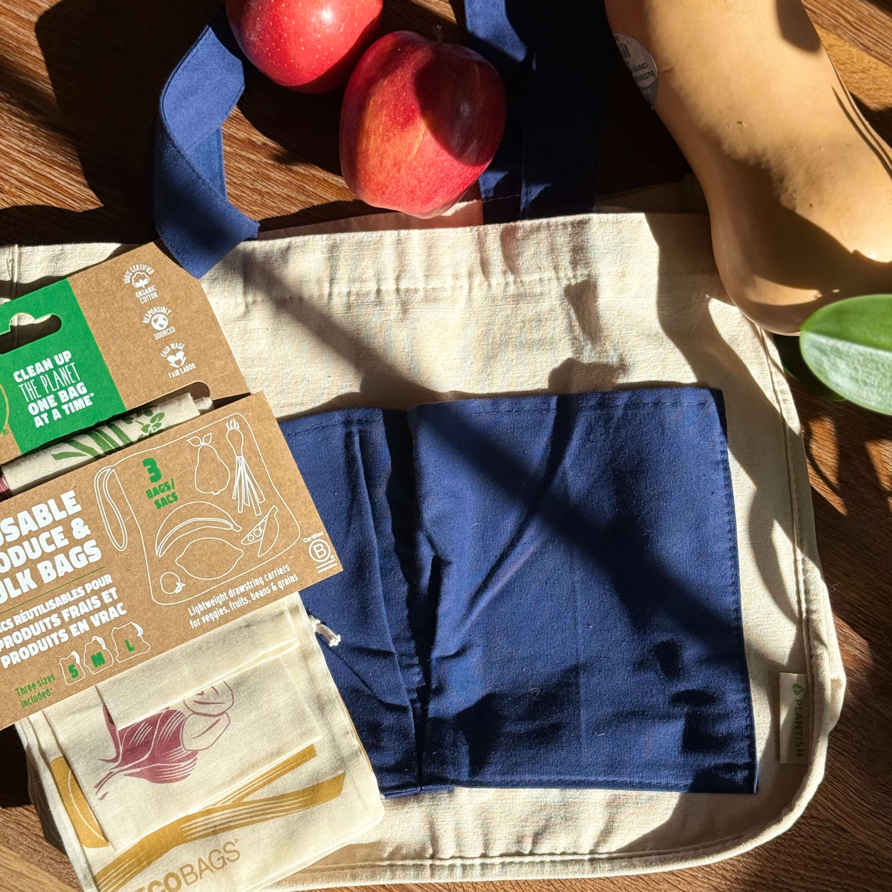 Reusable produce bags with apples on a wooden surface, featuring eco-friendly packaging.