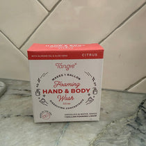 A box of Tangie Hand & Body Foaming Soap in Citrus scent, placed diagonally on a tiled floor.