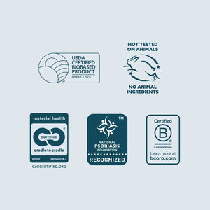 A set of six dark teal certification and marketing badges arranged on a pale blue background. The badges include USDA Certified Biobased Product, Not Tested on Animals / No Animal Ingredients, Material Health Certified Silver, National Psoriasis Foundation Recognized, and Certified by B Corp Corporation.