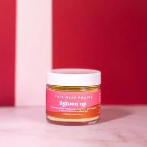 Jar of 'Lighten Up' face mask powder on a pink background