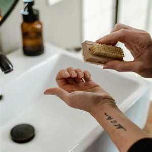 Person scrubbing a sponge over their hand in front of a sink.