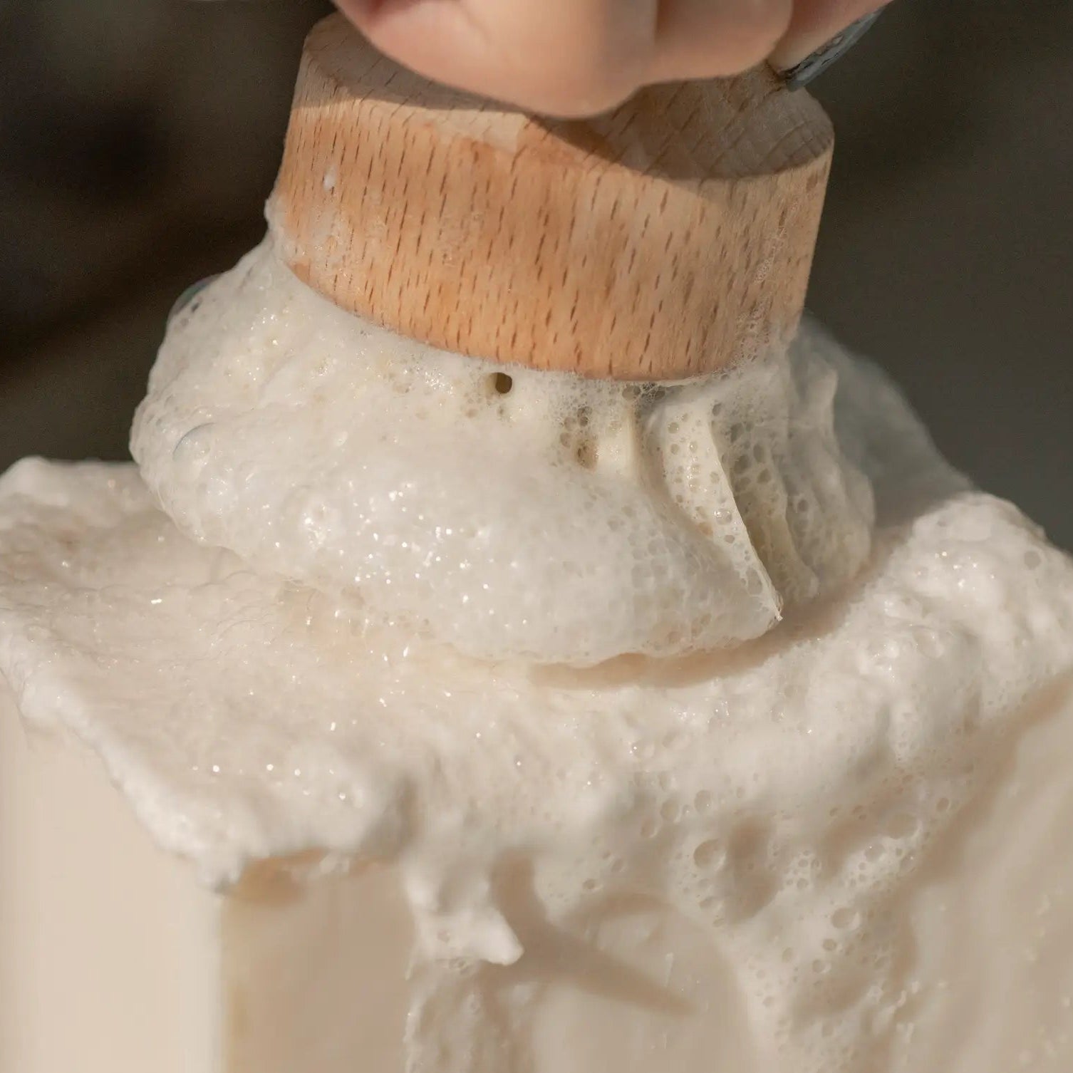 Close-up of a dish soap bar with a wooden handle being held.