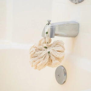 Knitted soap saver hanging on a wall-mounted soap holder with a white background