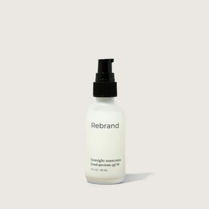 Sunscreen bottle labeled 'Rebrand' on a light gray background