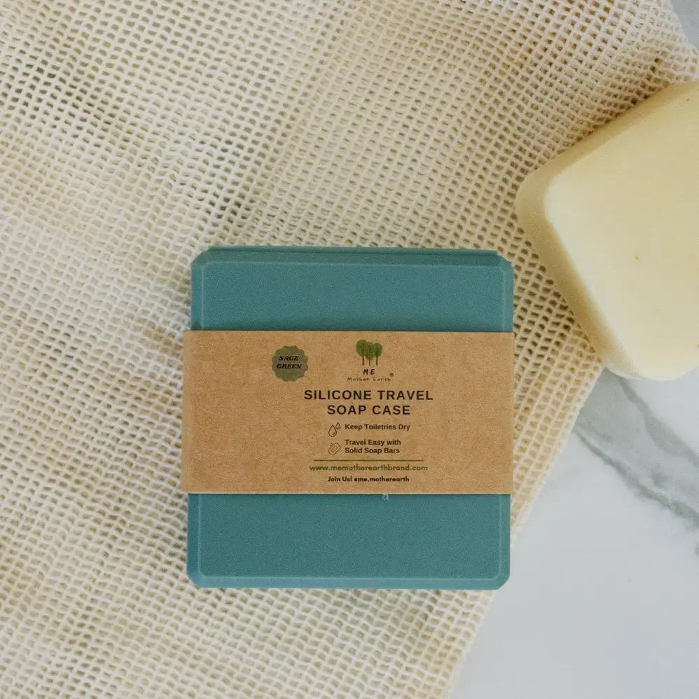 A teal silicone travel soap case with a kraft paper band label, placed on a textured cream mesh fabric next to a bar of soap.