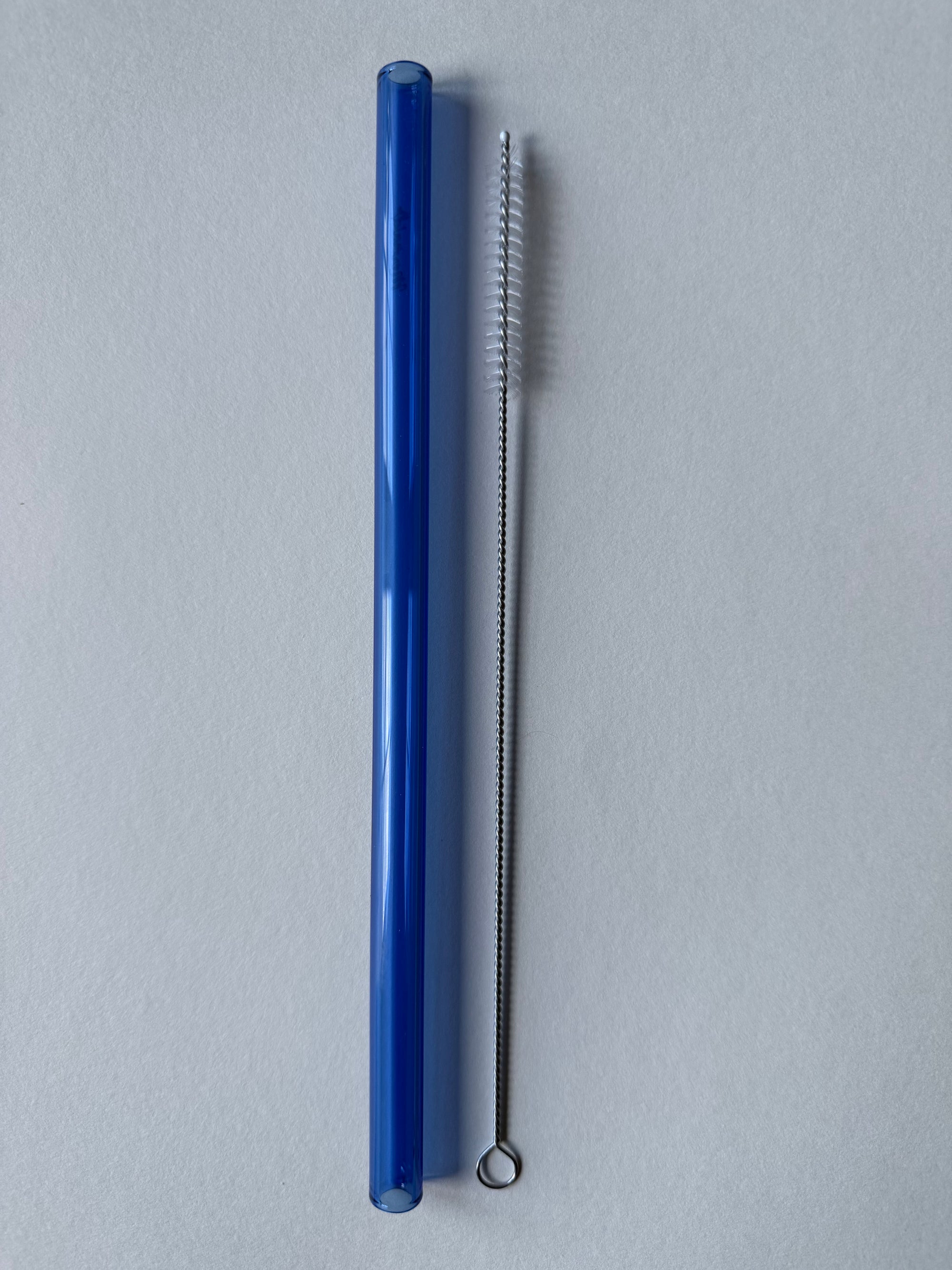Blue glass straw and cleaning brush on a white background
