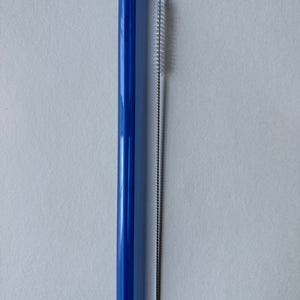 Blue glass straw and cleaning brush on a white background