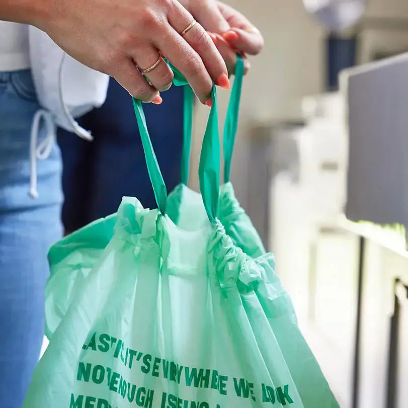 Person holding a green reusable bag with text.