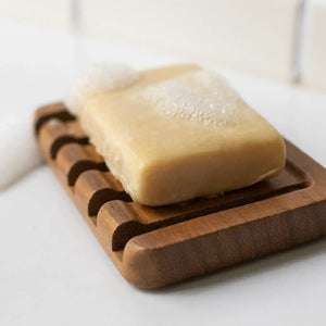 Bar of soap on a wooden soap dish with a blurred background
