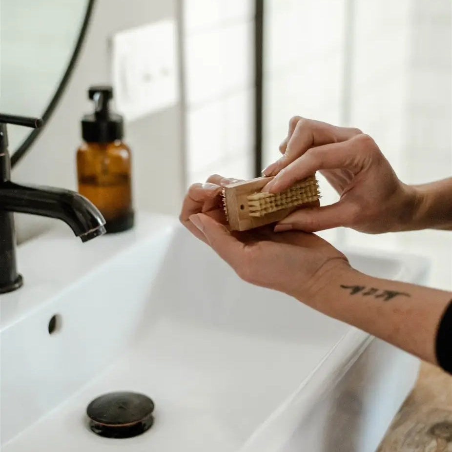 Person holding a bar of soap over a white sink with a blurred background