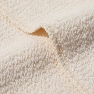 A close-up of a soft, textured cream-colored terry cotton fabric, showing the detailed loop pile and a folded corner.