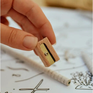 A hand handing a wooden pencil sharpener