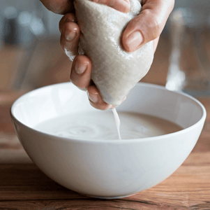 Hands pressing an organic cotton bag to make your own nut milk
