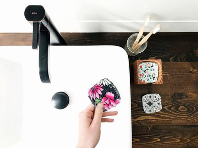 Hand holding a facial round above a bathroom sink